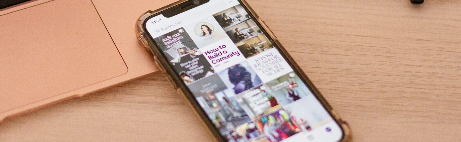 A smartphone with an article about "How to Build a Community" is on a wooden desk next to a laptop and a pair of eyeglasses, showcasing the intersection of technology and personal connection in the context of ethical AI in personalized marketing.