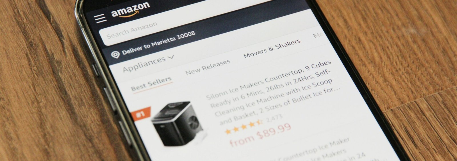 iphone sitting on a wooden table showing an amazon page with products that are different prices meant to represent dynamic pricing